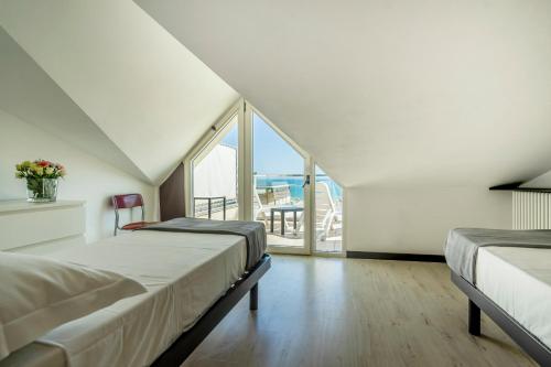 two beds in a room with a large window at Hotel Cristallo in Rimini
