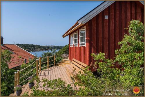a red house with a wooden deck next to a river at Hem till Bengt in Kungshamn
