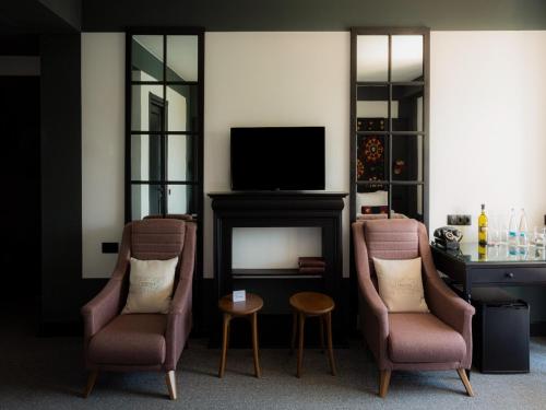 a living room with two chairs and a television at Esquisse Design Hotel in Tʼelavi