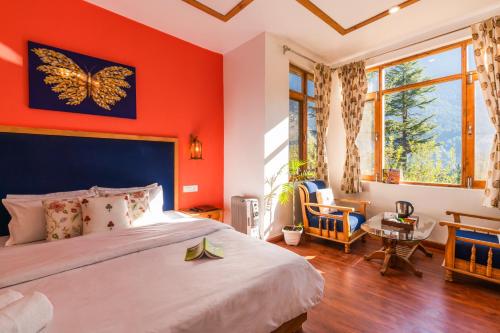 a bedroom with red walls and a bed with a butterfly painting on the wall at Zen Manali by Keekoo Stays in Manāli