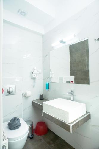 a white bathroom with a sink and a toilet at Lux VIP Apartments in Perea