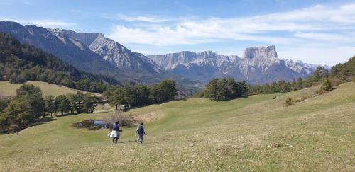 two people walking on a hill with mountains in the background at Les Vagabonds du Mont in Chichilianne