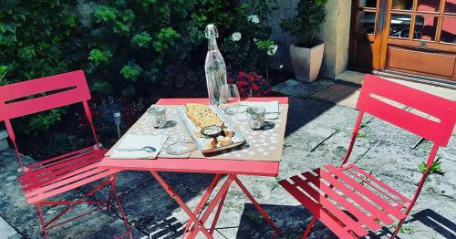 a red table with a bottle and two chairs at Les Vagabonds du Mont in Chichilianne
