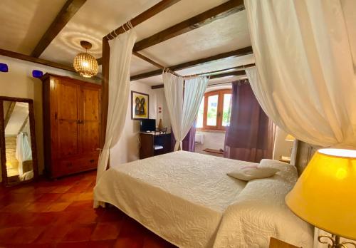 a bedroom with a white bed with curtains at Vign'Alva in Castelsardo
