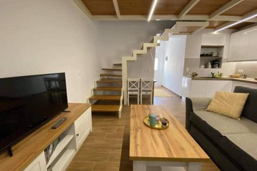 ein Wohnzimmer mit einem Sofa, einem TV und einem Tisch in der Unterkunft CasaDiNova1 in Paradeísion