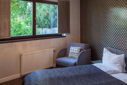 a bedroom with a bed and a chair and a window at Apartamentowiec Panorama Gór City Center Family&Pet-friendly in Szklarska Poręba