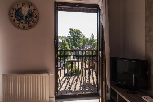 a door to a balcony with a table and a clock at Apartamentowiec Panorama Gór City Center Family&Pet-friendly in Szklarska Poręba