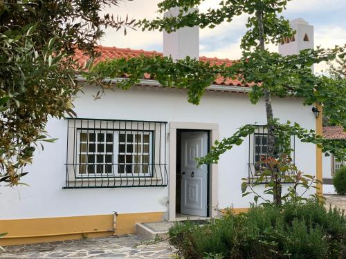 uma casa branca com uma porta preta e janelas em Quinta dos Girassóis FZ em Ferreira do Zêzere