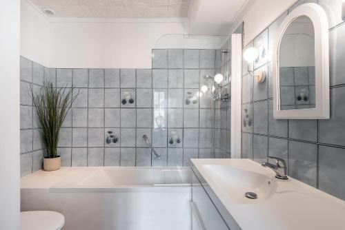 a white bathroom with a tub and a sink at L'escalier rouge - Maison rénovée avec cour in Luc-sur-Mer