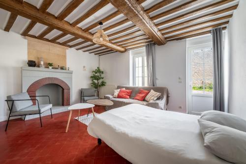 a bedroom with a bed and a living room with a fireplace at L'escalier rouge - Maison rénovée avec cour in Luc-sur-Mer
