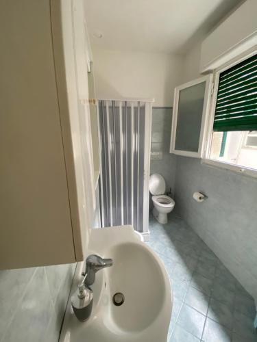 a white bathroom with a sink and a toilet at La casa del pescatore in Viareggio