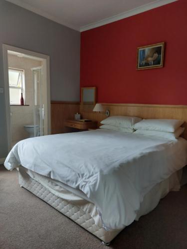 
a bedroom with a white bed and white walls at Clifford House B & B in Rosslare
