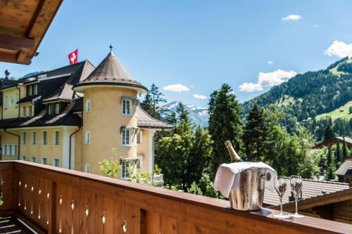a table with wine glasses and a bottle on a balcony at Le Grand Bellevue in Gstaad