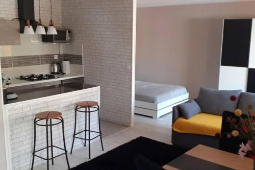 Il comprend une cuisine et un salon avec un canapé et un tabouret. dans l'établissement Charmante petite maison, à Charleville-Mézières