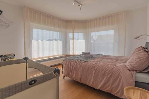 1 dormitorio con cama y ventana grande en Vakantiewoning voor 12 met garages terras tuin en Blankenberge
