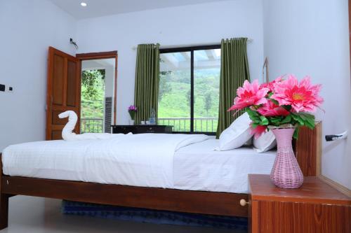 ムンナルにあるPeace Valley Home Stayのベッドルーム1室(花瓶のあるテーブル付)