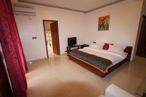1 dormitorio con 1 cama y TV en Residence MASSOU en Yaundé