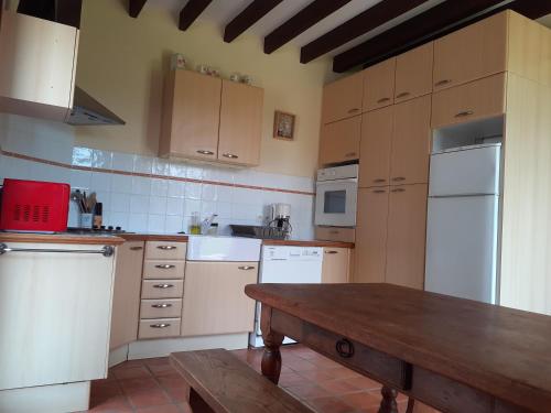 - une cuisine avec des appareils blancs et une table en bois dans l'établissement La Maison de l'Isle, à Eu