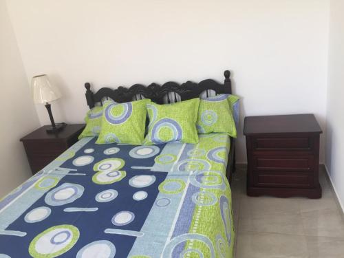 a bedroom with a bed with green and blue pillows at Casa Bella-suit in Ciudadela Costa de Oro