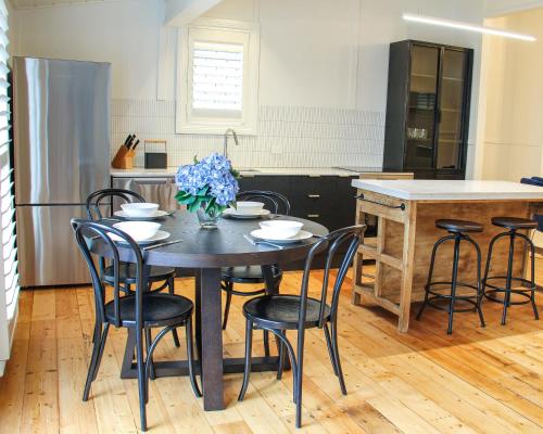 a kitchen with a table with chairs and a vase of flowers at Alexander Cottage Daylesford in Daylesford