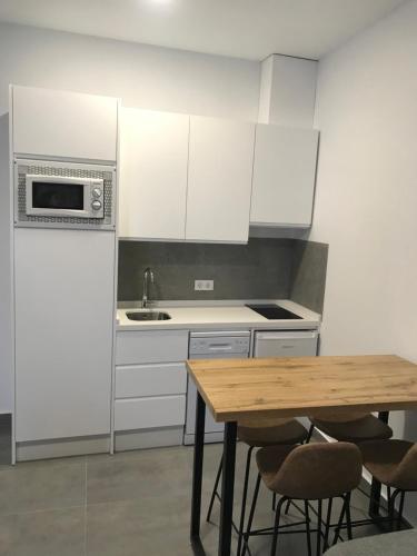 a kitchen with a wooden table and a microwave at Apartamentos Ad Theatrum in Mérida