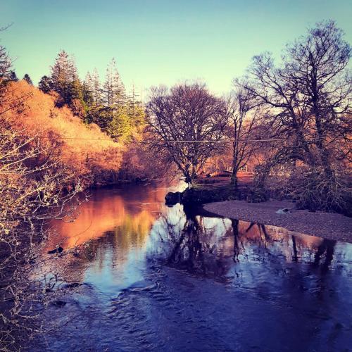 a river with a bridge and some trees and water at Glenorchy Lodge Hotel-Rooms Only in Dalmally