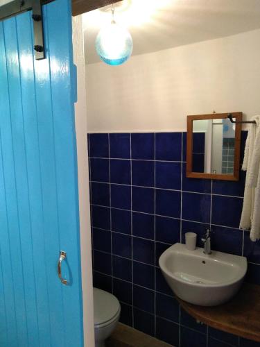a blue tiled bathroom with a sink and a toilet at Piccola Casa Di Sardegna in Villanova Monteleone
