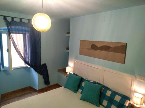 ein Schlafzimmer mit einem Bett mit grünen Kissen und einem Fenster in der Unterkunft Piccola Casa Di Sardegna in Villanova Monteleone