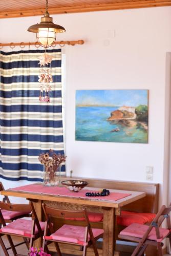 a dining room table with pink chairs and a painting at Options House in Hydra