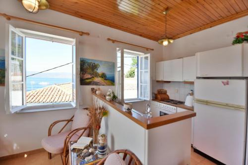 a kitchen with white appliances and windows and a table at Options House in Hydra