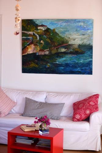 a painting above a white couch with a red coffee table at Options House in Hydra