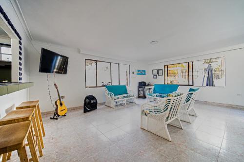 a living room with chairs and a tv and a guitar at Hostal Palo Alto in San Andrés