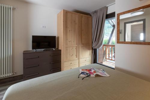 1 dormitorio con 1 cama, TV y espejo en Residenza Betulla, en Bormio