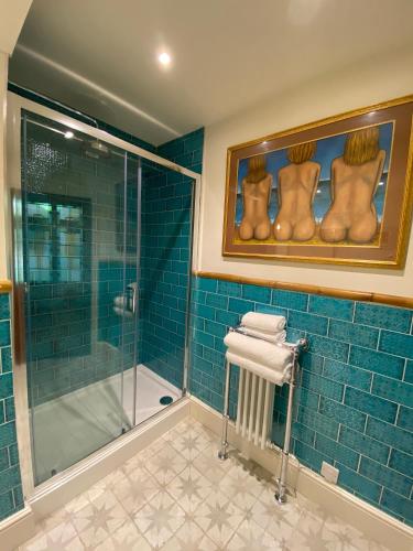 a bathroom with a shower and blue tile at Tolcarne Beach Colonial Restaurant and Rooms in Newquay