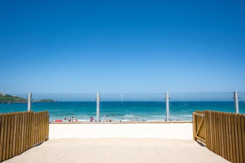 a beach with a view of the ocean and people at Tolcarne Beach Colonial Restaurant and Rooms in Newquay