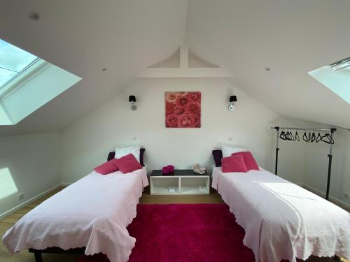 two beds in a room with white walls and pink pillows at Villa du bassin -un petit coin de paradis in Andernos-les-Bains