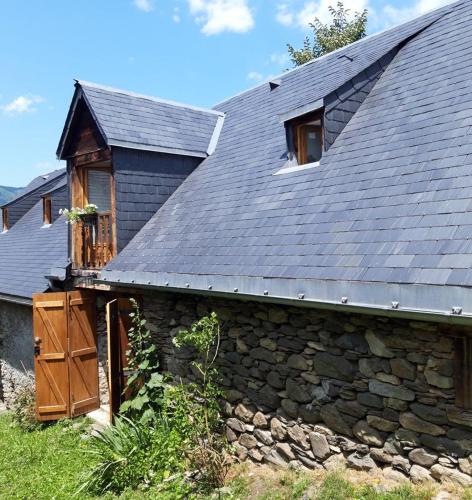 uma casa de pedra com um telhado de ardósia e uma janela em La grange Loudervielle Louron Pyrénées em Loudenvielle