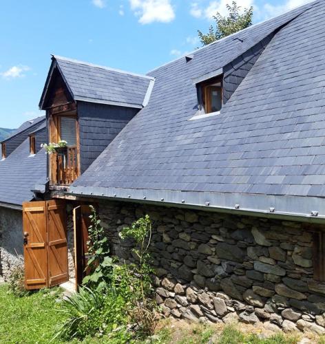 a stone house with a slate roof and a window at La grange Loudervielle Louron Pyrénées in Loudenvielle