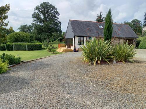 a house with a gravel driveway in front of it at La Gasteboisiere with swimming pool and games room in Le Mesnil-Adelée