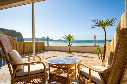 a patio with chairs and a table and the beach at Tolcarne Beach Colonial Restaurant and Rooms in Newquay