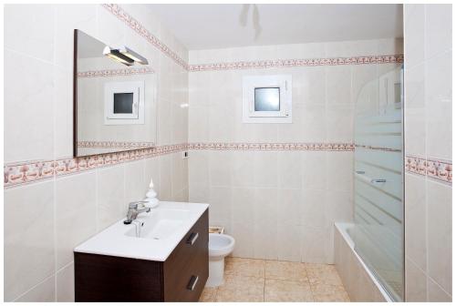 La salle de bains est pourvue d'un lavabo, de toilettes et d'un miroir. dans l'établissement BINI SEGUI · Villa amplia 12 pax · 6 hab · 4 baños · Piscina privada, à Binibeca