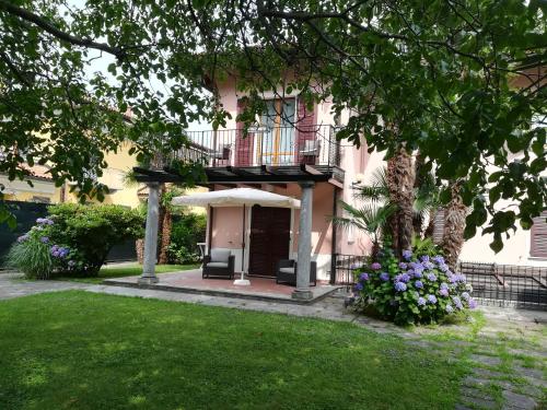 a pink building with a balcony and flowers in a yard at Residence Villa Margherita WITH POOL & HYDROMASSAGE in Cannobio