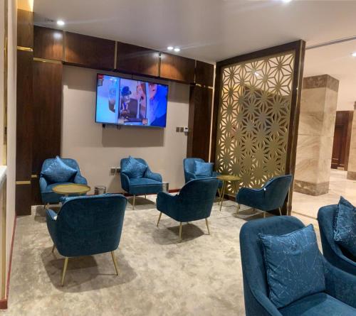 a waiting room with blue chairs and a flat screen tv at Cladium Hotel in Medina