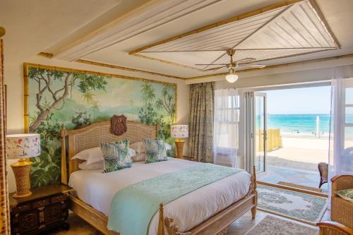 a bedroom with a bed and a view of the ocean at Tolcarne Beach Colonial Restaurant and Rooms in Newquay