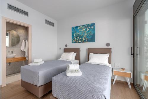 two beds in a room with a bathroom at Messinian Riviera Villas in Petalidhion
