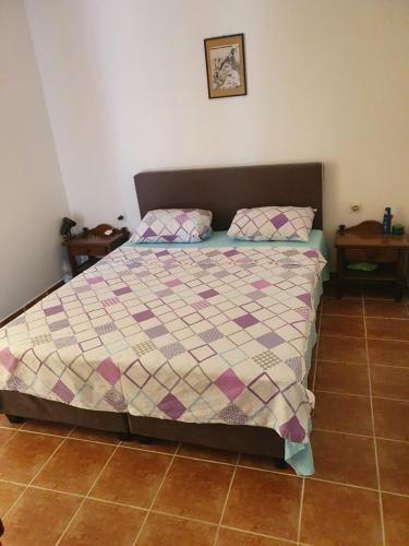 a bedroom with a bed with a quilt and two tables at Apartmani NAR in Sutomore