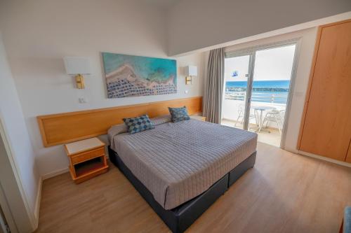 Schlafzimmer mit einem Bett und Meerblick in der Unterkunft Tylos Beach Hotel in Kato Pyrgos