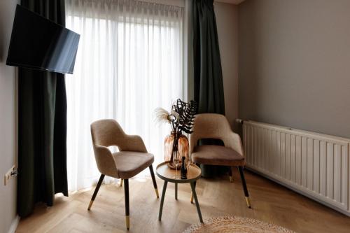 a living room with two chairs and a table and a window at Hotel Karsten in Norg