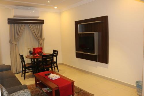 a living room with a couch and a table and a television at Al-Fakhamah Hotel Apartments - Families Only in Al Khobar