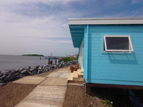 a blue building next to the water with a window at Waterhuisjes op de pier van LauwersmeerPlezier! in Lauwersoog
